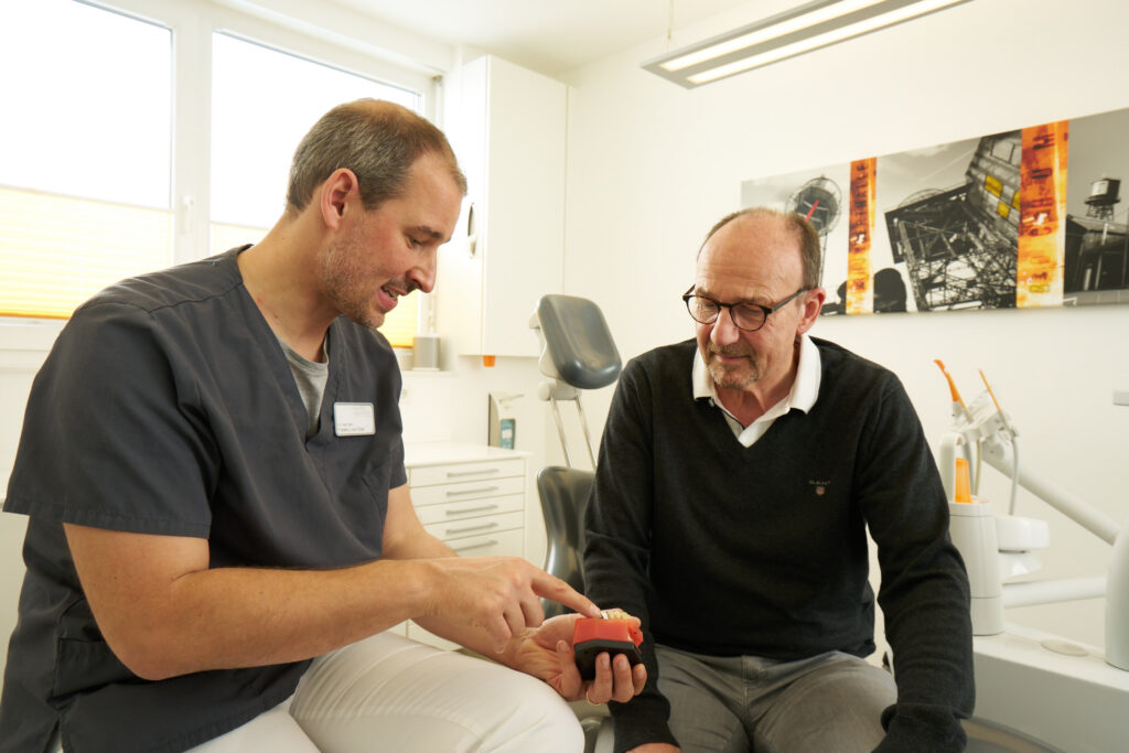 Dr. vom Orde berät einen Patienten zum Zahnersatz mit einem Implantat oder einer Brücke.